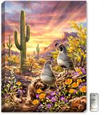 A warm and appealing painting of desert quail, with sunset colors, desert wildflowers, cactus, and large rock formations.